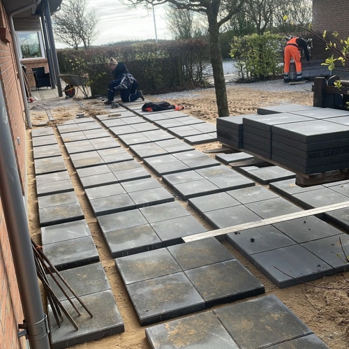 Belægning med sorte fliser under lægning i Hurup nær Thisted af erfarne brolæggere