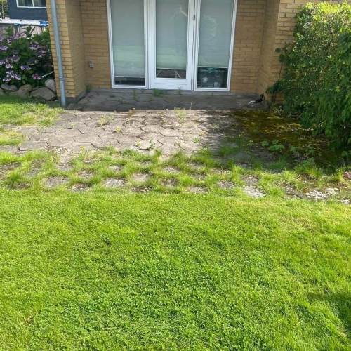 Terrasse før ny belægning i Hurup nær Thisted med slidte fliser og mosvækst